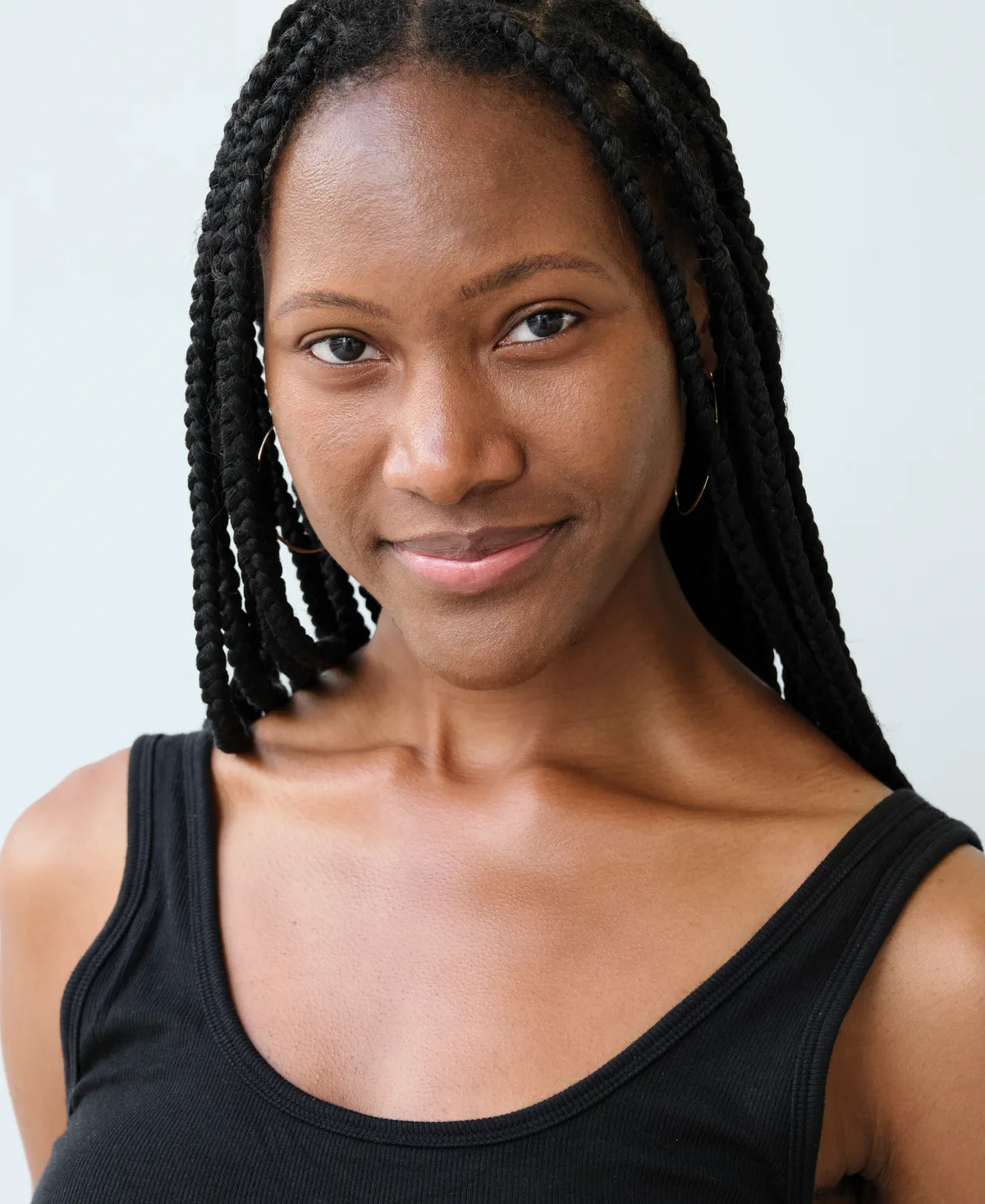 Ahdis Beruk with braids in a black tank top, portrait treated in coral